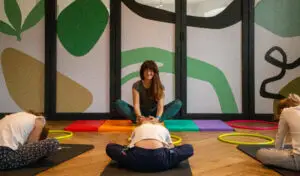 Un groupe de trois filles s'incline en avant lors d'un cours de yoga.