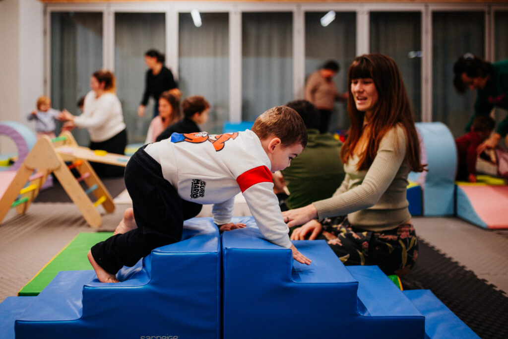 Un enfant monte un module escalier afin de le redescendre de l'autre côté, lors d'un atelier de Baby Gym