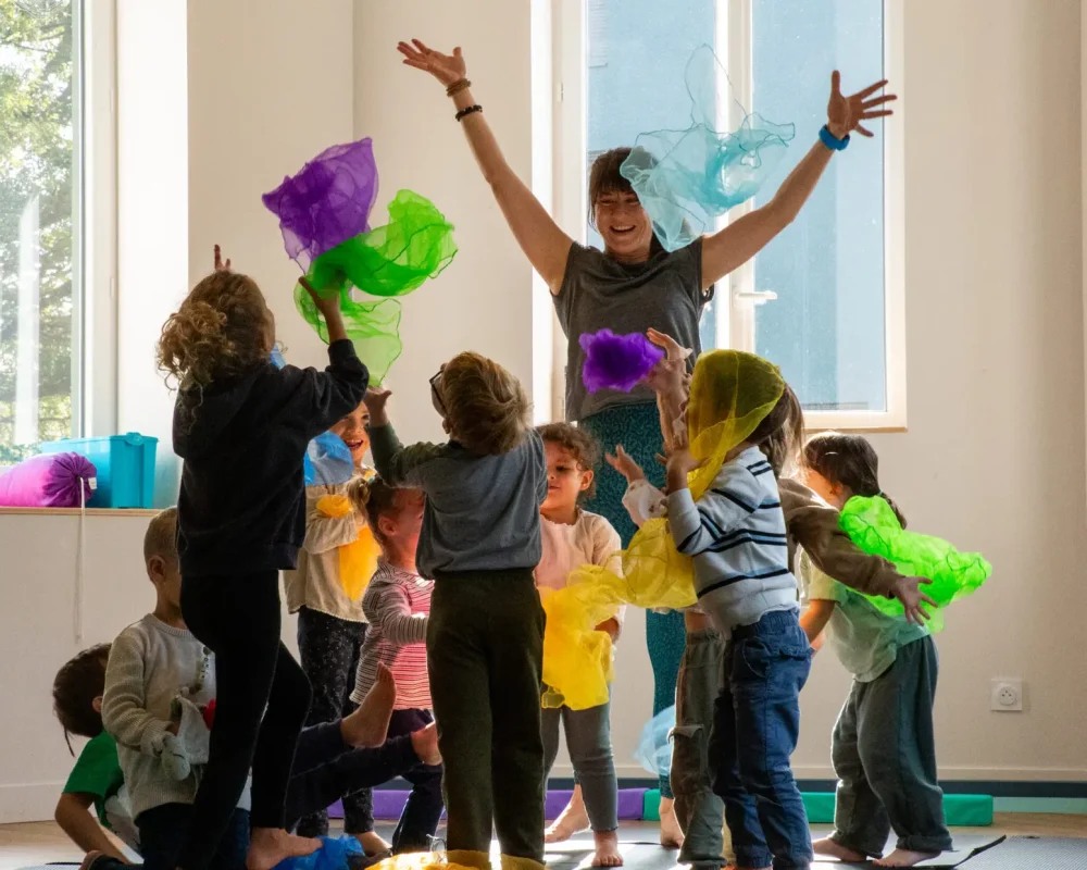 Un groupe d'enfants jette en l'air des chiffons colorés lors d'un atelier de cirque.